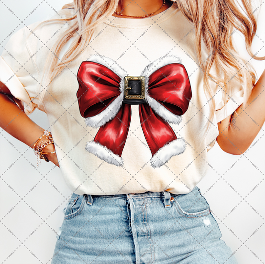 A person in a beige T-shirt adorned with a prominent red bow trimmed with white fur and featuring a decorative buckle is matched with light blue jeans. Their long, wavy hair adds harmony to the ensemble as they pose against the transparent background of the Christmas Coquette Bow PNG file.