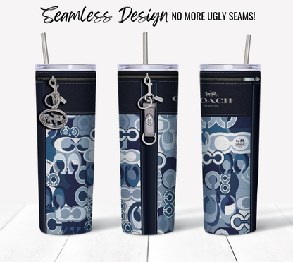 Three NY Coach Navy Leather Blue Monogram Fabric Texture 20 oz Skinny Sublimation Tumblers with straws stand side by side on a light wooden surface. Each tumbler features a blue and white seamless pattern and a silver keychain hanging from the lid. The text above them reads "Seamless Design - No More Ugly Seams!".